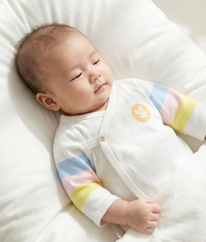 Baby wearing HIPZOO off-white wrap-style jeogori with blue, pink and yellow saekdong sleeve stripes